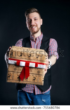 Man holding box with Christmas gifts in hands. Bearded hipster gives Christmas gifts. Christmas sale, discounts on purchases. A man with a beard gives presents