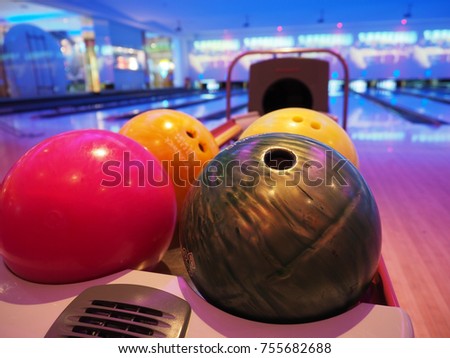 Bowling background. Interior of bowling alley lane with balls return machine closeup, selective focus on blue ball