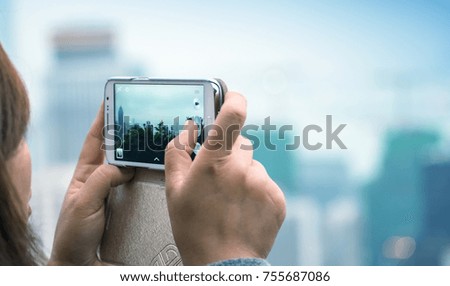 Woman taking city picture with her smartphone.