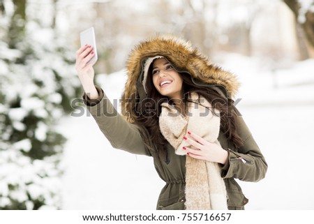 Pretty young woman taking selfie with mobile phone on a cold winter day