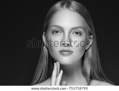 Young girl face beauty skin portrait with long blonde hair with hand over dark background. Studio shot.
