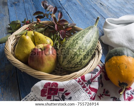 Pears, apples and pumpkins in a basket on an old blue painted background