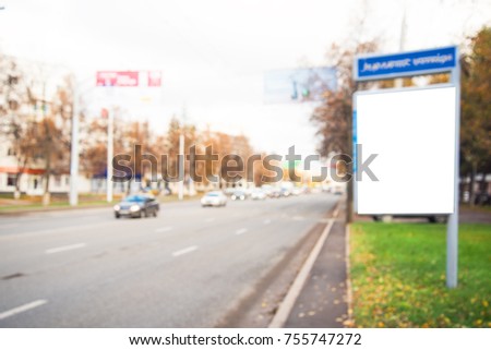 Blank billboard near road with cars and near trees in town