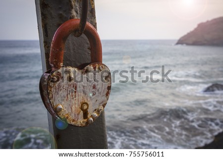 old red lock of love on the bridge on the background of sea and sky