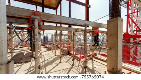 high building under construction with workers in the construction site on supports wearing safety uniform