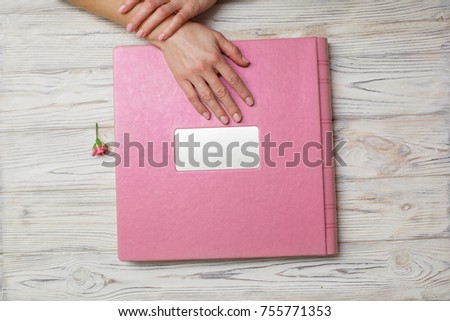photobook with a hard cover on a wooden background.
leather  photo album with a shield on the wooden surface .
photoalbum in the hands .
a woman holds a family  photo book.
