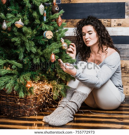 Beautiful romantic girl sits near the Christmas tree. Christmas and New Year concept