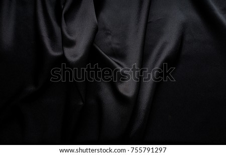 Dark black silky, satin fabric, wave, draperies. Beautiful textile backdrop to create creative layouts for black Friday. Close-up. Top view