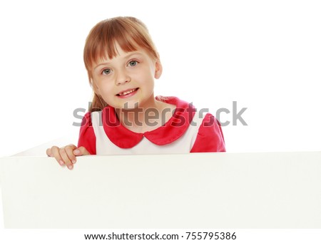 A little girl is looking from behind an empty banner.