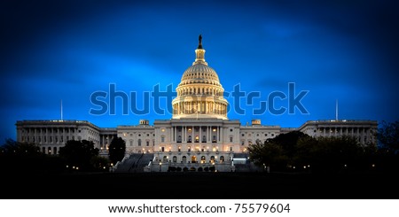 The United States Capitol building with the dome lit up at night.  Both the Senate and House sides of the building are fully shown. Royalty-Free Stock Photo #75579604