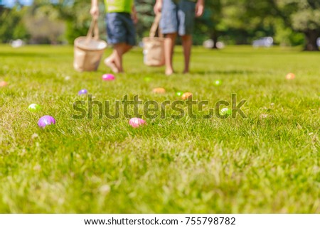 easter eggs hunt blurred background. Blurred silhouettes of children with baskets in hands. in the foreground colorful plastic eggs with surprises inside