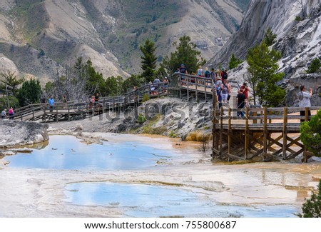 Mammoth hot springs pools with boardwalk, walkway. Tourists, people walking, taking pictures