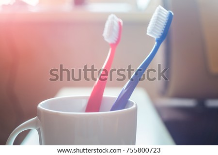 Close-up of Red and Blue Plastic Toothbrushes in White Mug on Blurred Background Concept Dental Royalty-Free Stock Photo #755800723