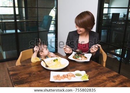 Asian girl twenty months eating breakfast with her mom at home office, portrait mom and daughter feeling happy together concept. Mom and daughter having breakfast at the office.