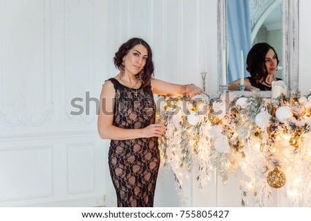 Young smiling beautiful woman near a Christmas decoration on Christmas eve at home.