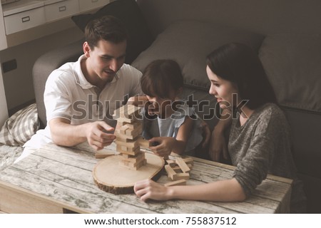 Mother and father playing puzzle game with their daughter in living room together. Family fun time concept. Royalty-Free Stock Photo #755837512