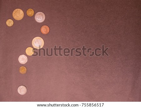 A question mark is laid out from various small coins. Where can I get money, cash? On the right is free space, gray background, daylight.