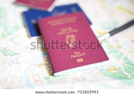 Assortment of passports placed on a map with a pen, passports include UK, Republic of Ireland and Australian