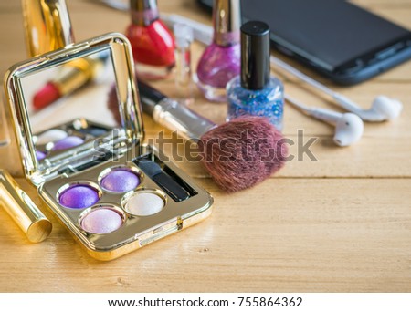Eyeshadow, brush, lipstick on a vintage wooden table. Set of beautiful women's cosmetics on the table.