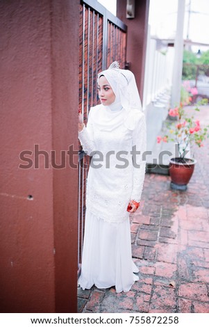 Portrait of young attractive woman in white hijab and dress with crown smiling at outdoor