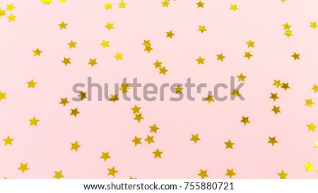 Golden star sprinkles on pink. Festive holiday background. Celebration concept. Top view, flat lay. Horizontal, wide screen format