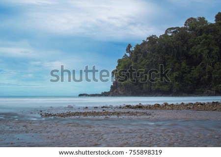 Beach on the pacific ocean in Costa Rica. Long exposure of the sea on Bahia Ballena beach with mountains in the background.
