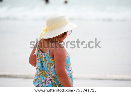 Little cute girl staying up on the beach