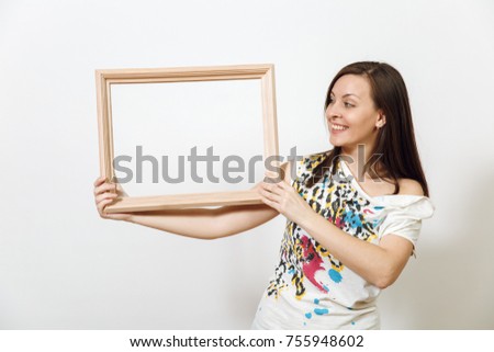The portrait of a happy smiling brown-haired woman standing and holding empty wooden frame on the white background. With place for text for advertising.
