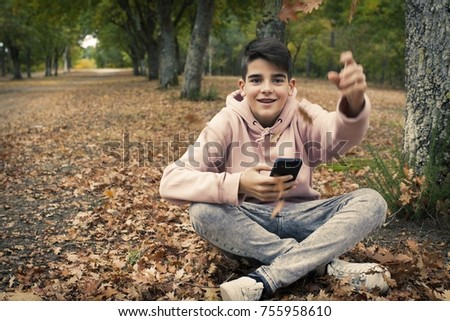 young teenager with mobile phone in the park in the fall