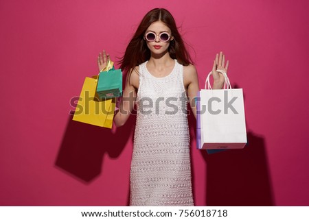   young beautiful red-haired woman on a pink background with multi-colored packages, shopping, beauty, style                             