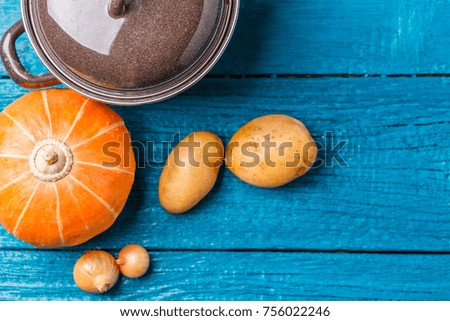 Image of pot with lid, potatoes, pumpkin, onions