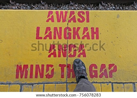 Awasi Langkah Anda in Malay means "Mind the gap"  is an visual warning phrase issued to rail passengers to take caution while crossing the horizontal,  Royalty-Free Stock Photo #756078283
