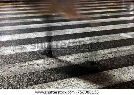 Rainy city street reflections: One young fragile female disappearing while crossing the wet street in the sparkling night Royalty-Free Stock Photo #756088135