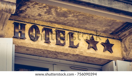 hotel sign on a stone wall with two stars in France