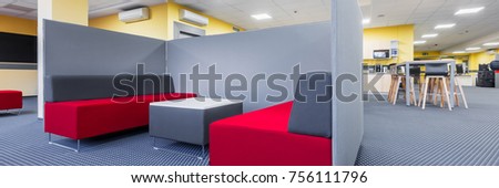 Panorama of library lounge area with red sofa, table and grey partition
