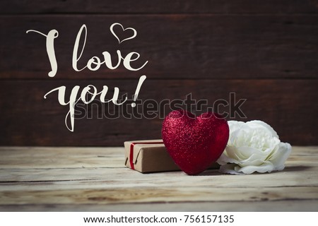 Concept Valentine's Day with the inscription I love you. Heart, gift, white rose on a wooden background.