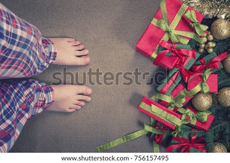 Merry Christmas and Happy New Year! Top view of a male legs in checkered pajamas with Christmas gifts.
