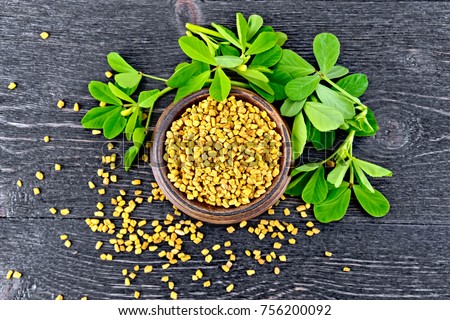 Fenugreek seeds in a bowl with green leaves on a wooden plank background on top Royalty-Free Stock Photo #756200092