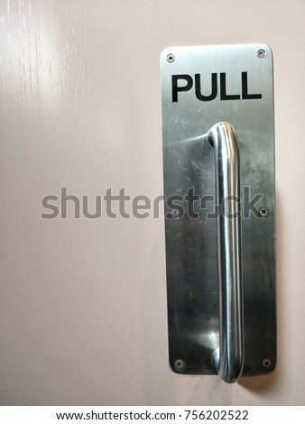 Metal door handle and word is "Pull" 