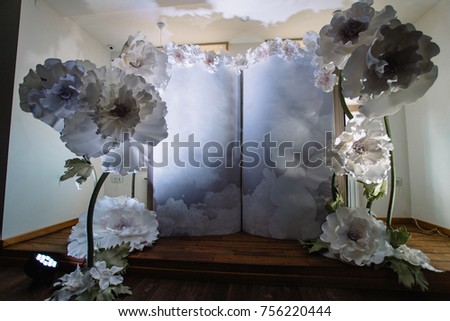 Wall decorated with white paper flowers and large book for a child