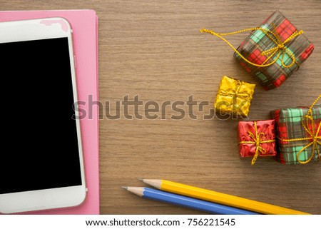 holiday decorations items,gifts boxes,ornaments on office wooden desk and smart phone for holiday gifts. flat lay,top view