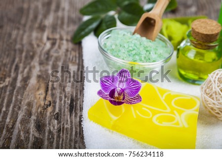 Spa treatments on an old wooden table. Sea salt, soap and orchid close-up. 