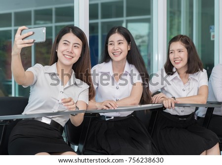 Cute asian young student in uniform sitting in a row to make funny selfie, lifestyle in university concept