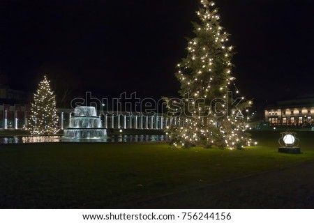 Night view on Bowling Green park with fontain and Christmas firs against Kurhaus colonnade background. Wiesbaden, Germany. 
