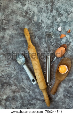 Accessories for baking a whisk, rolling pin, spoon and eggs, a concept of homemade hand-made cooking on a light marble background with a copy-space view from above
