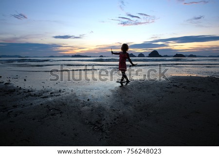 Silhouette of the little girl playing at the sunset shore. Thailand. Krabi. Tubkaek beach