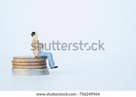 Close up of business and finance concept on gray background. Businessman miniature figure toy sit on stack of coins. 
