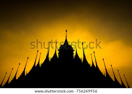 silhouette view of the top of temple in Thailand, yellow rays