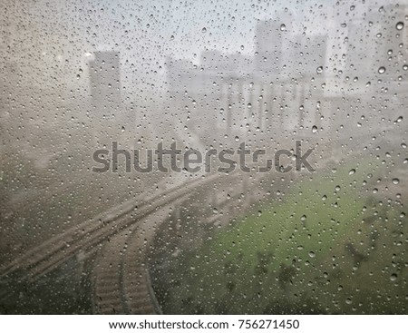 Soft image of rain scene view through office window glass. Soft focus due to gloomy low light during rainy evening environment. Rain droplets on external of glass. Gradient blur background.