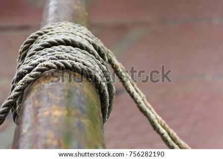 Textured coarse rope around wood.